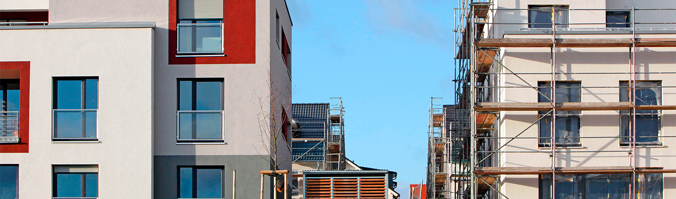 Moderne Einfamilienhäuser mit hellem Außenputz in Iserlohn, gepflegte Fassaden und klare Architektur unter blauem Himmel.