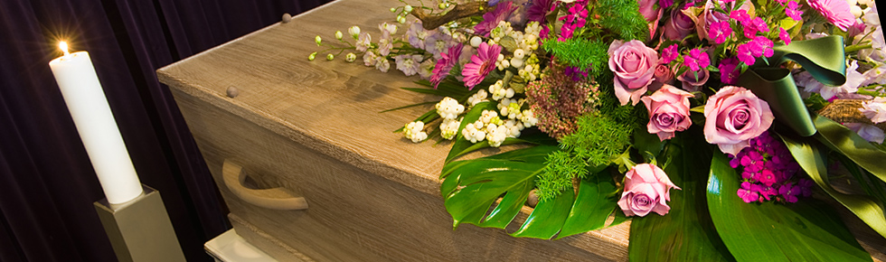 Sarg mit floralem Arrangement in der Leichenhalle