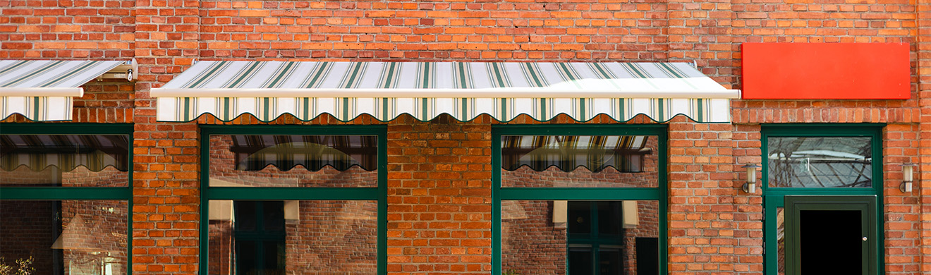 Outdoor-Café mit stilvoller Markise in Iserlohn, Tischen, Stühlen und grünen Pflanzen, sonniger Tag, gemütliche Atmosphäre.