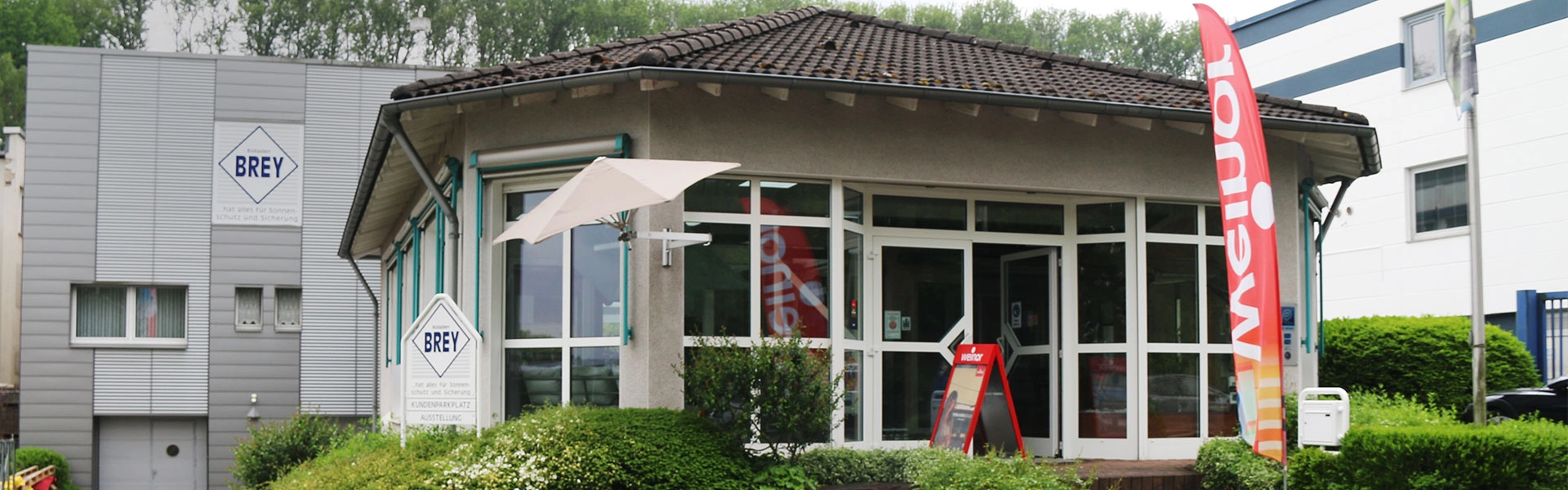 Firmengebäude und Ausstellungsraum von Rolladen Brey in Iserlohn mit Sonnenschutz  und Markisen Produkten im Außenbereich bei Tageslicht.